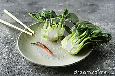Baby bok choi halves on a plate on gray background Stock Photo