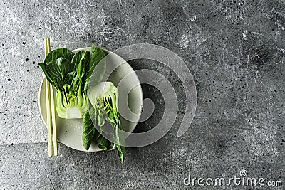 Baby bok choi halves on a plate gray background. Top view, horizontal orientation with copy space Stock Photo