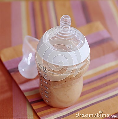 Baby bottle full of apricot milk Stock Photo