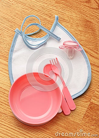 Baby bowl, spoon and fork with dummy Stock Photo
