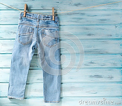 Baby boy blue jeans hanging on a clothesline on blue wooden background Stock Photo