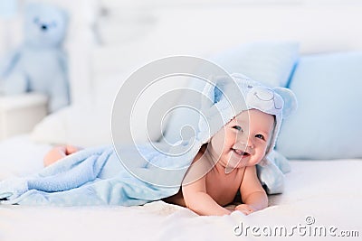 Baby boy in blue towel on white bed Stock Photo