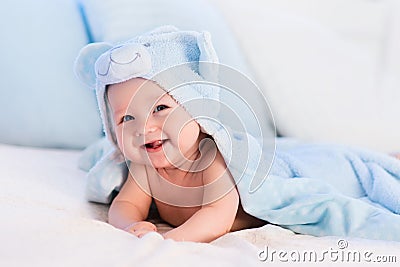 Baby boy in blue towel on white bed Stock Photo