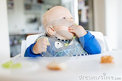 Baby boy eating with BLW method, baby led weaning Stock Photo