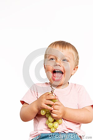 Baby boy eating grapes in the studio isolated on white background. Concept healthy fresh food Stock Photo