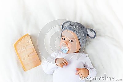 Baby boy in mouse hat lying on blanket with cheese Stock Photo