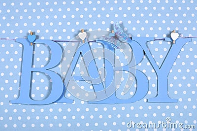 Baby boy nursery blue BABY letters bunting hanging from pegs on a line against a blue polka dot background Stock Photo