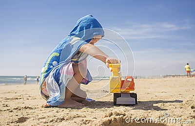 Baby boy playing on sand at the beach with excavator toy Stock Photo