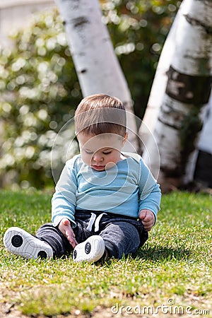 Baby boy sitting on grass in summer Stock Photo