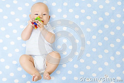 Baby Boy with Teether Toy In Mouth Lying over Blue Background, Happy Stock Photo