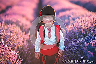 Baby boy in traditional Bulgarian folklore costume in lavender field. Working peasant during lavender harvest Stock Photo