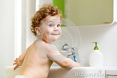 Baby brushing teeth in bathroom Stock Photo