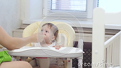 Baby is capricious and crying sitting on the highchair in kitchen. Stock Photo