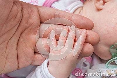 Baby care concept. Child holds hand of her father Stock Photo