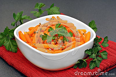 Baby carrots garnished with parsley in a white bowl. Stock Photo