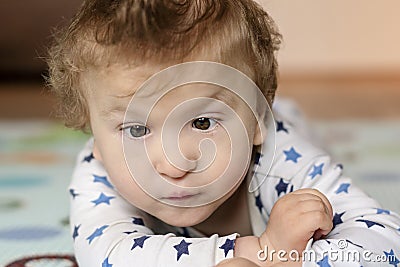 Baby with cerebral palsy lying on his belly and playing at home. Special needs child. Handicapped baby boy close-up Stock Photo