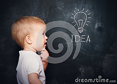 Baby child at the blackboard with chalk drawn bulb symbol ideas Stock Photo