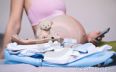 Baby clothes, necessities for mother and newborn in maternity bag. Pregnant woman getting ready for labor packing stuff for Stock Photo