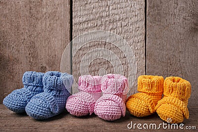 Baby concept: different colored baby booties, Three pairs of baby booties on a wooden background. Stock Photo