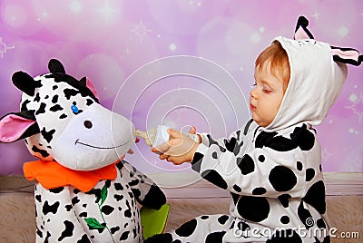 Baby in cow costume feeding a cow mascot Stock Photo