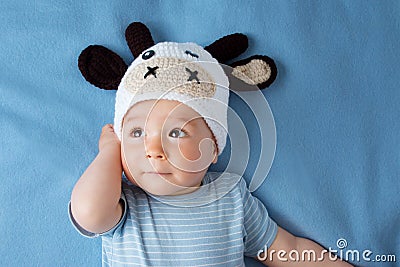 Baby in a cow hat on blue blanket Stock Photo