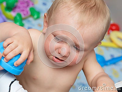 Baby cries holding a toy Stock Photo