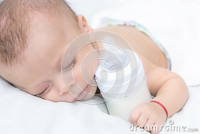 Baby curled up sleeping on a blanket with feeding bottle Stock Photo