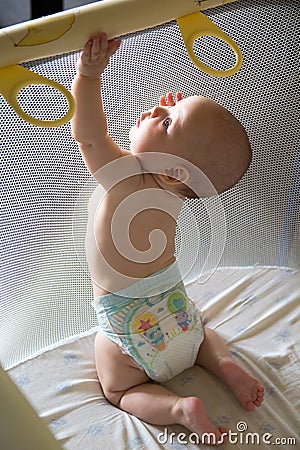 Baby in a diaper in playpen Stock Photo