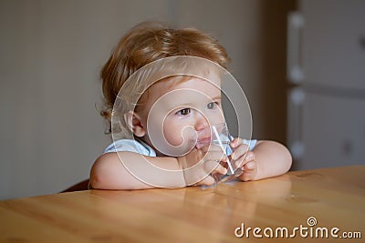 Baby drinking glass of water. Healthy nutrition for kids. Portrait of little baby having drink in domestic environment. Stock Photo