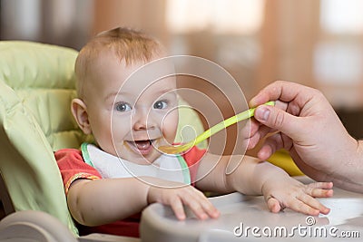 Baby eating food with father help Stock Photo