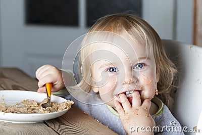 Baby eats porridge spoon mashed Stock Photo