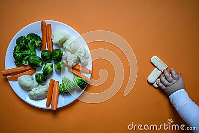 Baby eats vegetables and cookies Stock Photo