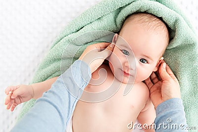 Baby face massage background. Mother gently stroking baby boy face with both hands. Close up cropped shot. Stock Photo