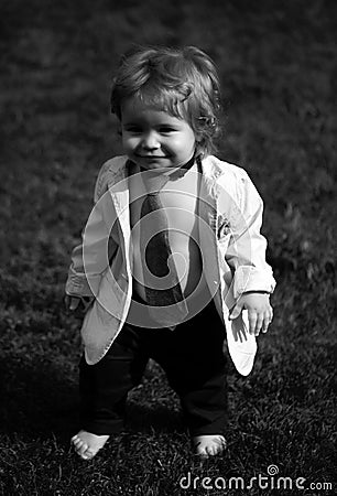 Baby fashion. Funny little business man in suit, jacket and necktie. Portrait of a little baby boy playing outdoor in Stock Photo