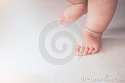 Baby feet doing the first step on the floor Stock Photo