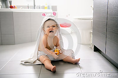 A baby girl in the bathroom at home crying Stock Photo