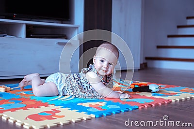 Baby girl doing tummy time on colorful play mat Stock Photo