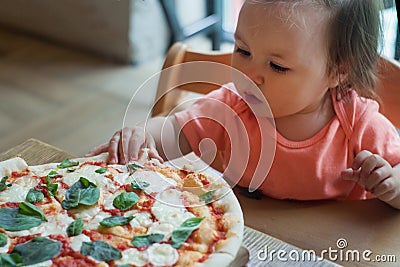 Baby girl eating pizza in italian restaurant, Healthy, unhealthy food, children`s fast food. Stock Photo