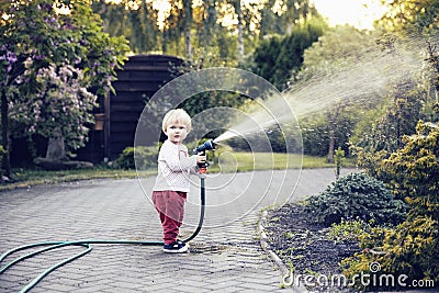 Baby girl with a garden hose Stock Photo