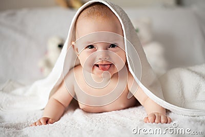 Baby girl is hiding under the white blanket. Stock Photo