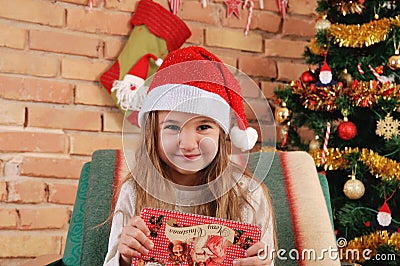 Baby girl with little red box in hands on the chair near Christmas tree Stock Photo