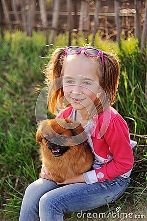 Baby girl with a pekinese sitting on the grass Stock Photo