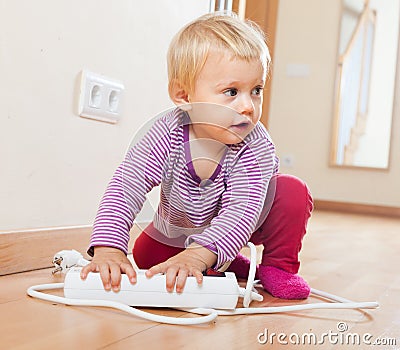 Baby girl playing with electrical extension Stock Photo