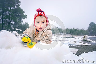 Baby girl plays with the snow lying Stock Photo