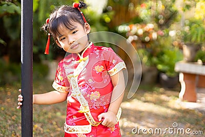 Baby girl in red Chinese outfit playing in garden Stock Photo