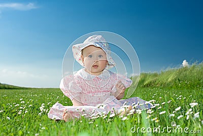 Baby girl sat in flowery field Stock Photo