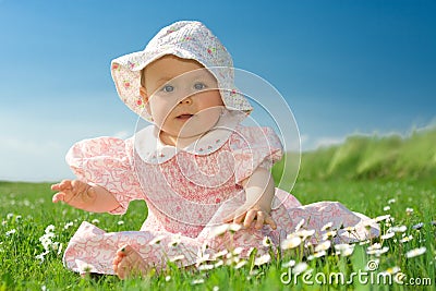 Baby girl sat in flowery field Stock Photo