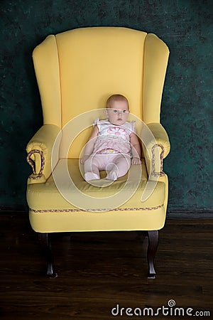 Baby Girl Sitting on Big Armchair in Studio Stock Photo