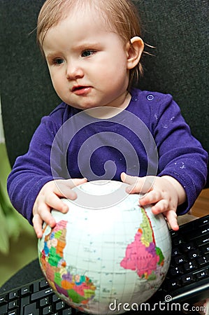 Baby girl sitting with computer keyboard and a globe Stock Photo