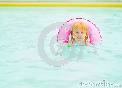 Baby girl with swim ring swimming in pool Stock Photo